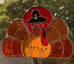 JGS turkey suncatcher hanging in window casting warm colored light into room, brightens space