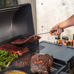 Traeger pig tail lifting ribs on grill demonstrating easier large-meat handling