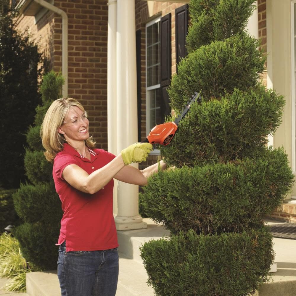 BLACK+DECKER trimming a small shrub, demonstrating controlled, lightweight cutting