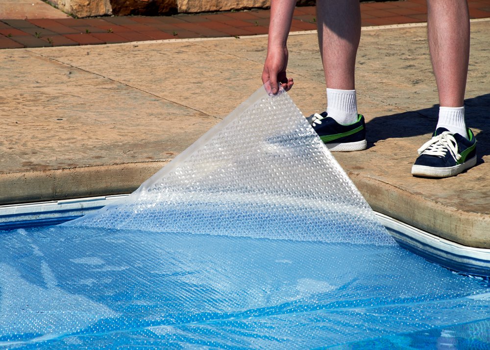 Blue Wave solar blanket laid on pool surface, reduced evaporation benefit