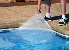Blue Wave solar blanket laid on pool surface, reduced evaporation benefit