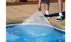 Blue Wave folded cover beside ruler, shows 12x24 ft scale and easy handling