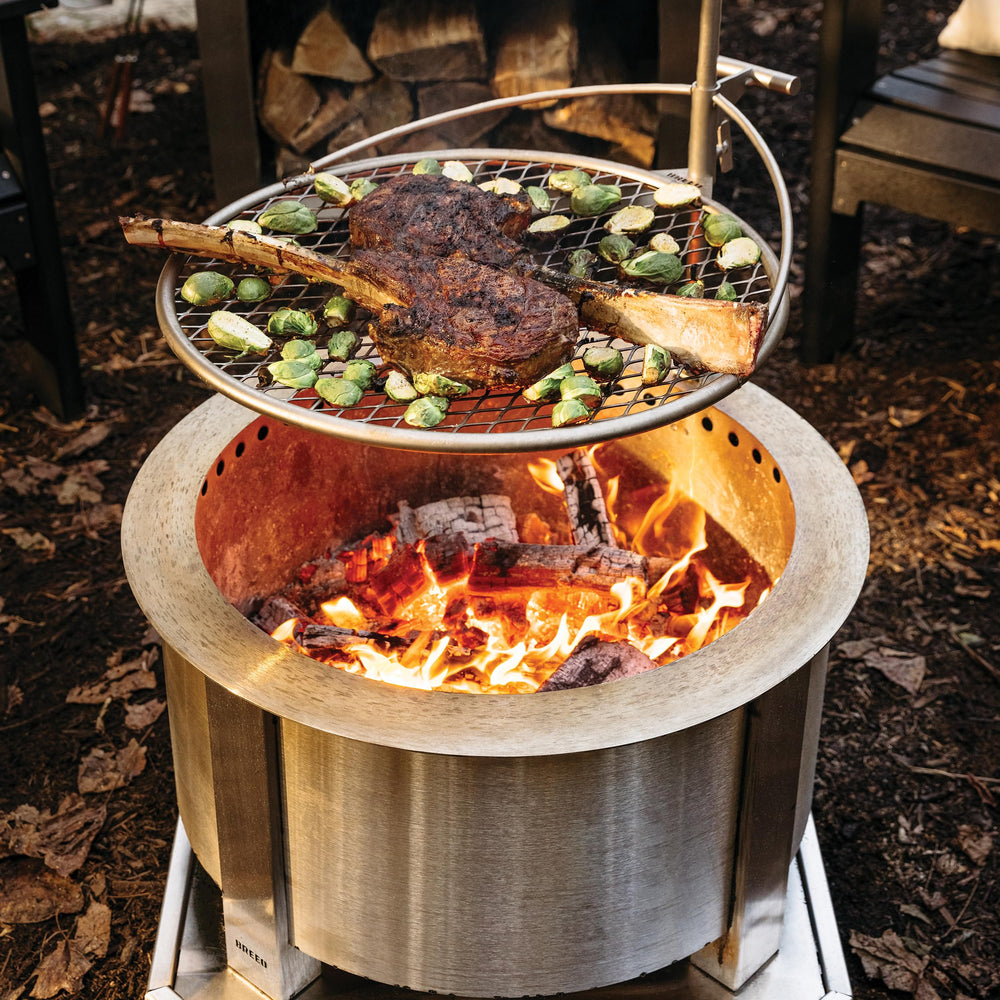 Breeo Outpost Grill 24 in campfire setting showing versatile outdoor cooking