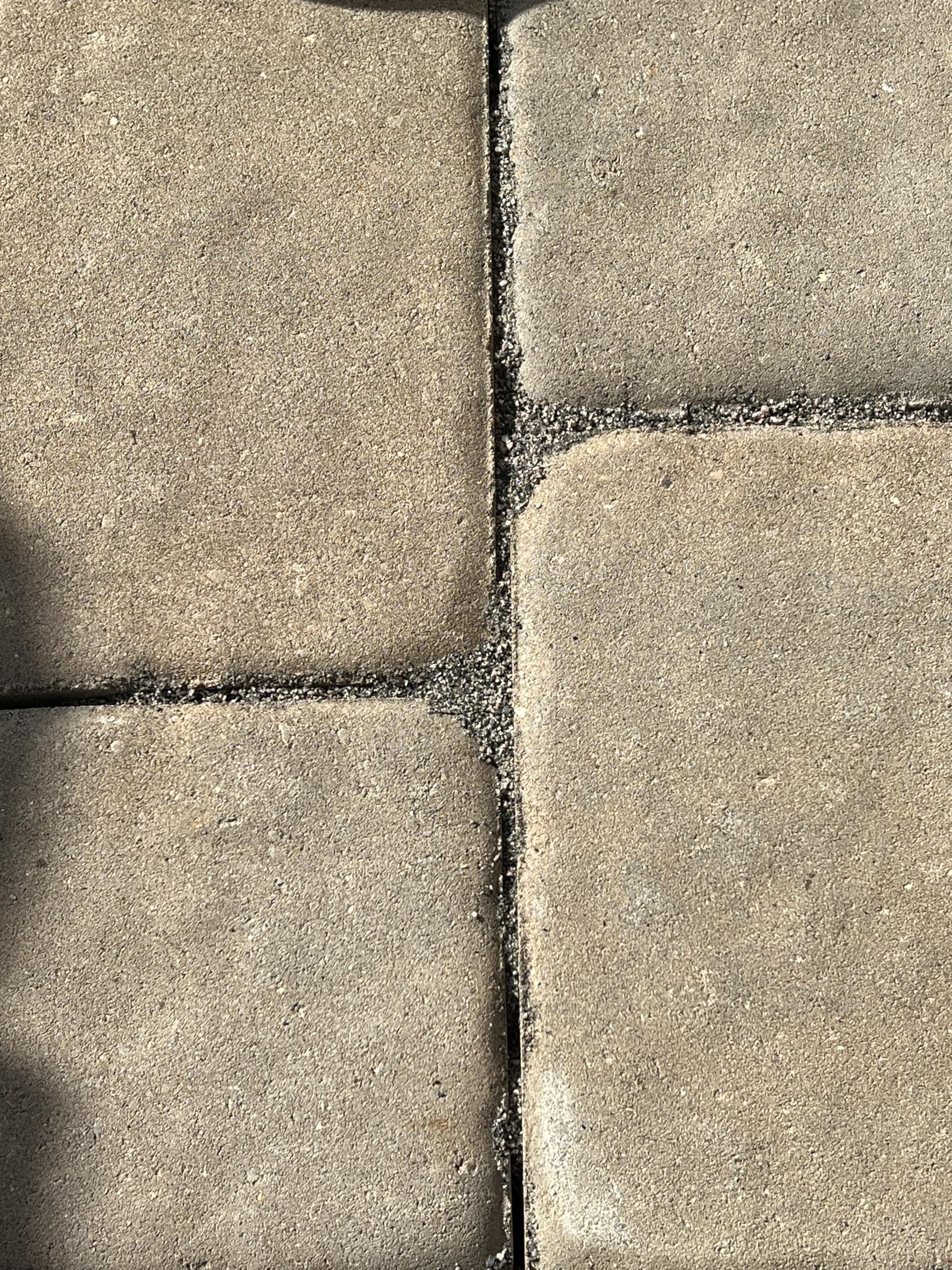 Worker sweeping BuddingCo sand into paver joints for easy installation and fast coverage
