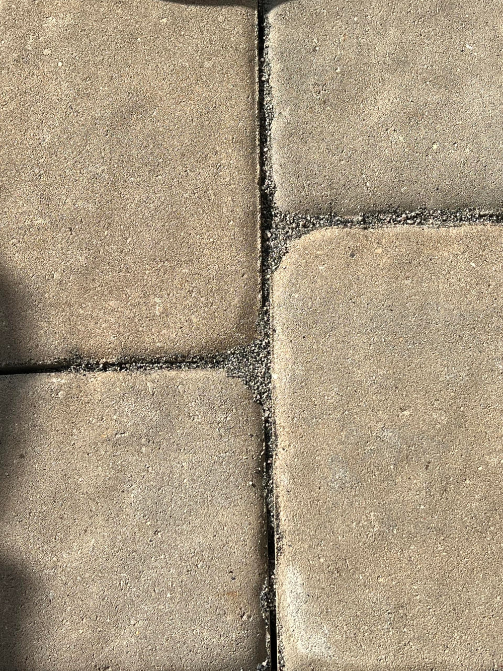 Worker sweeping BuddingCo sand into paver joints for easy installation and fast coverage