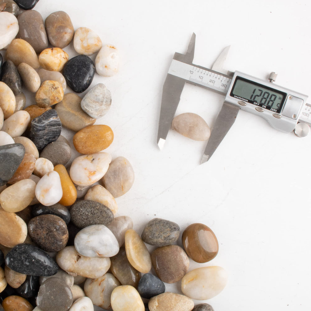 CJGQ hand holding pebble for scale illustrating 1–1.5 inch size and practical use
