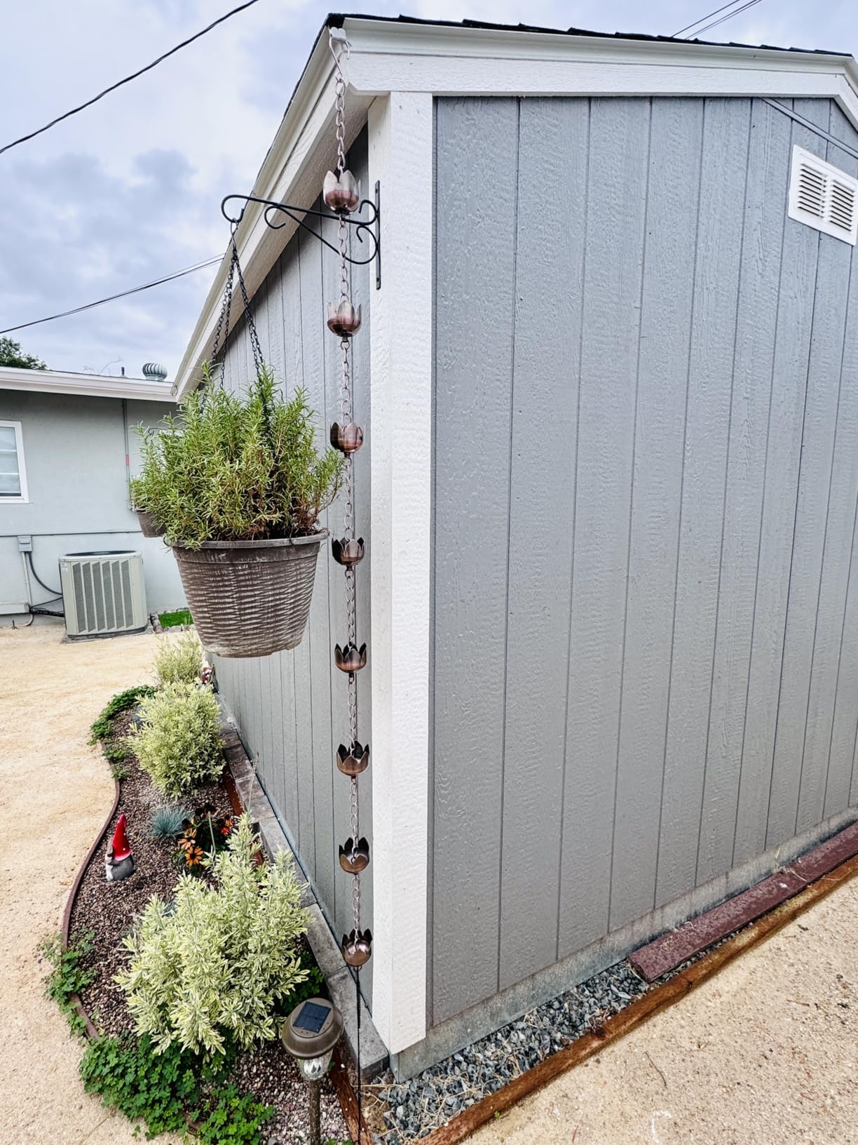 CLYB rain chain hanging on a porch in a garden setting showing decorative enhancement benefit