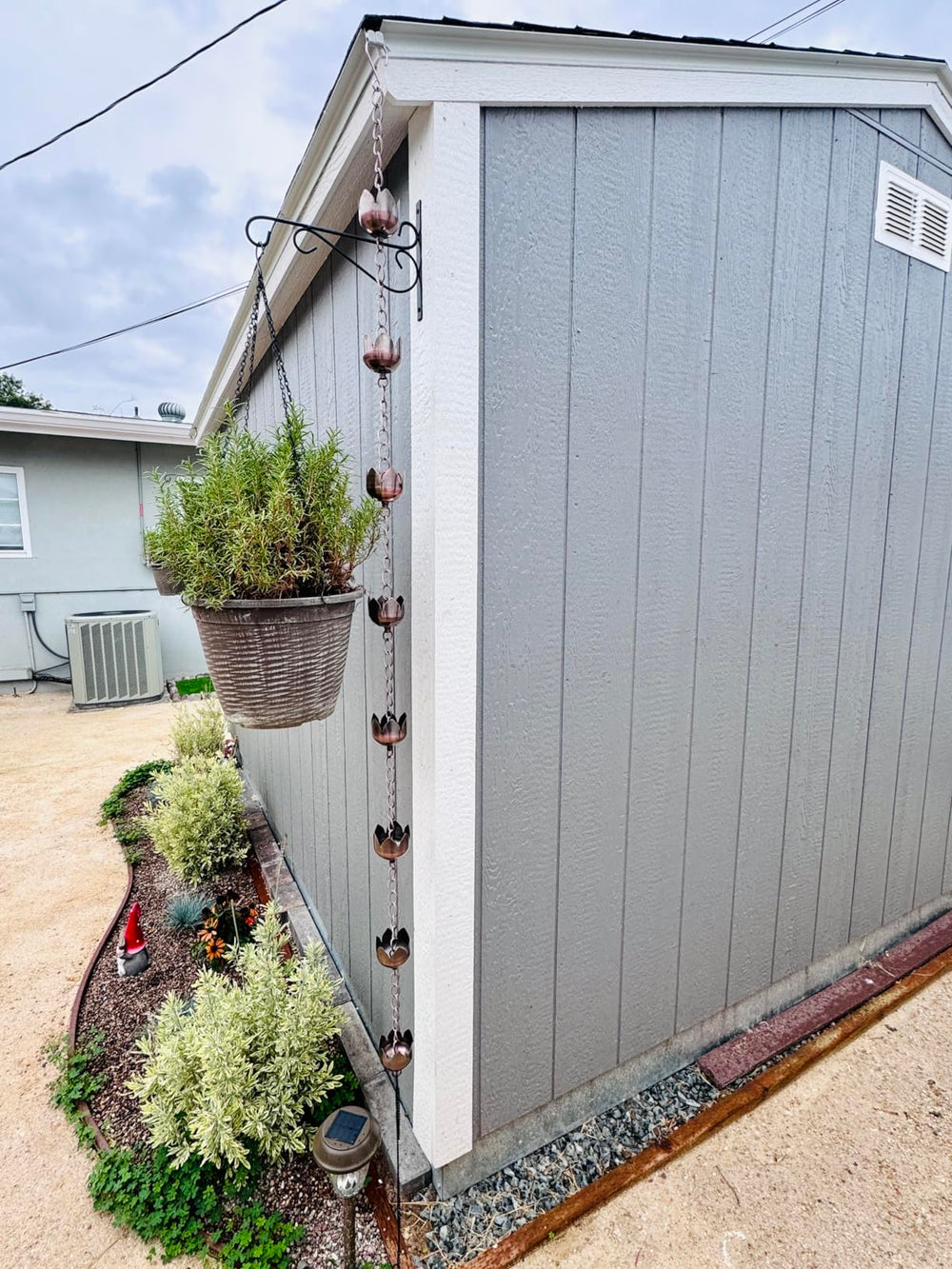 CLYB rain chain hanging on a porch in a garden setting showing decorative enhancement benefit