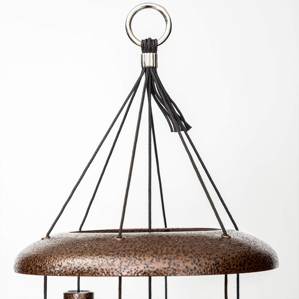 Corinthian Bells next to chair showing size scale and appropriate outdoor fit benefit