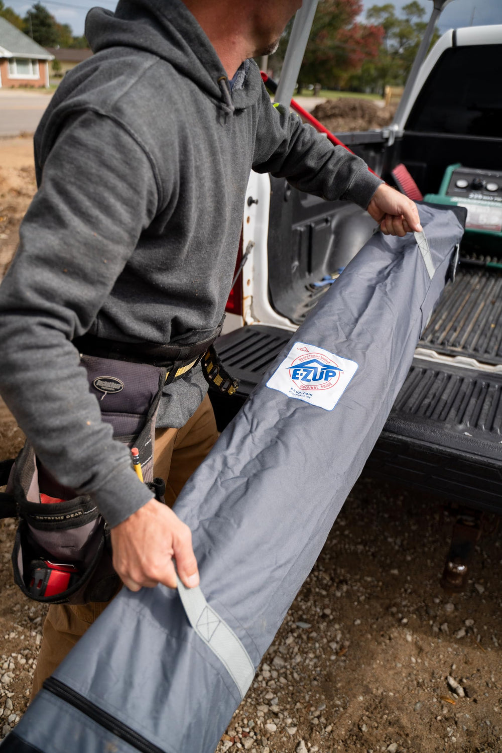 E-Z UP folded shelter beside a backpack showing compact collapsed storage advantage