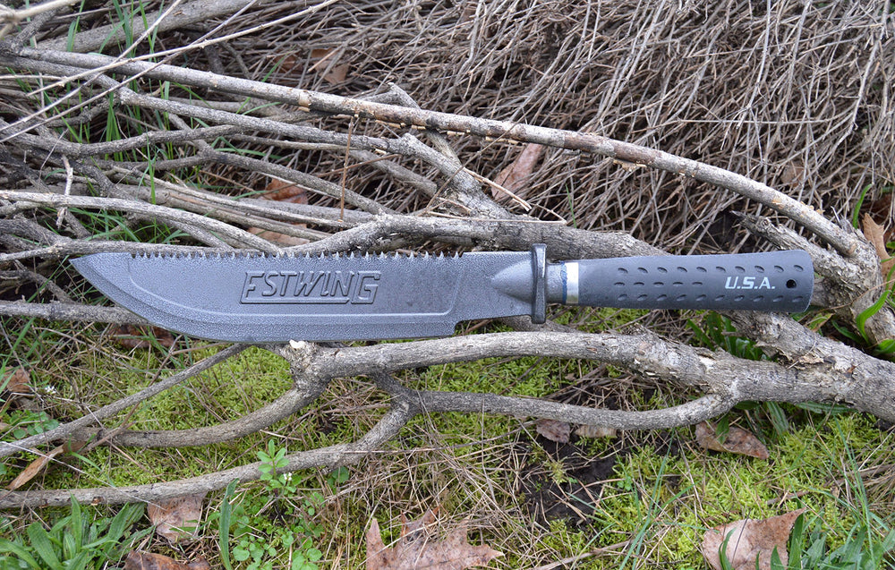 Estwing machete clearing brush in field demonstrating durable outdoor use