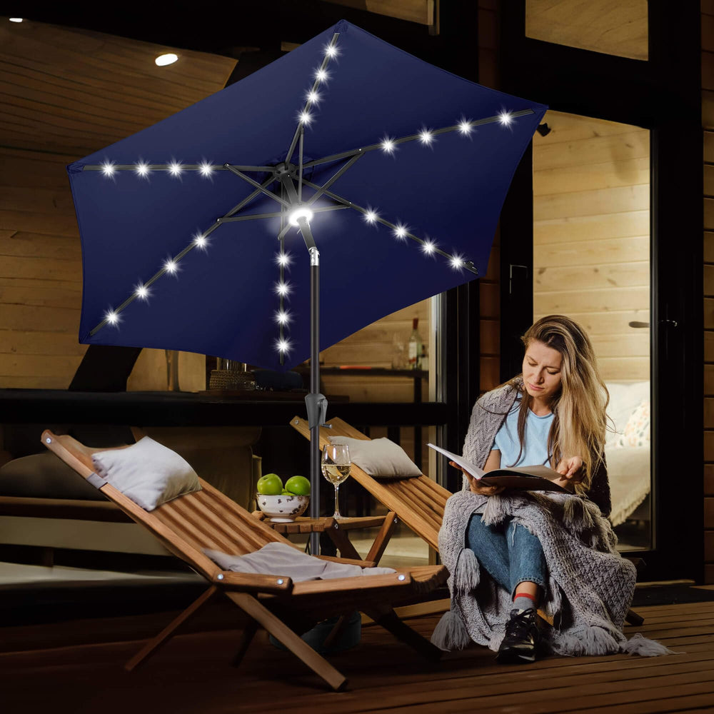 FLAME&SHADE umbrella lit over patio table at night creating warm ambiance