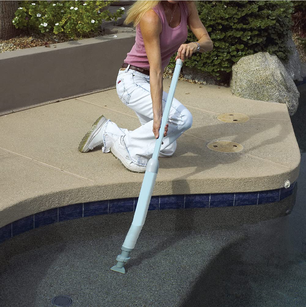 GAME handheld spa vac beside a hand for size comparison and easy handling