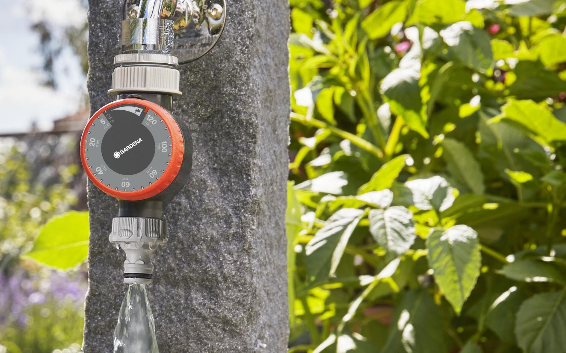 Gardena water timer attached to outdoor faucet powering a sprinkler for hands-free watering