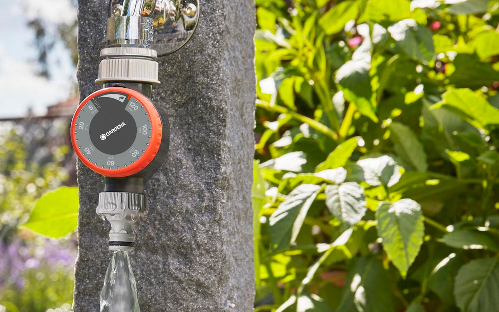 Gardena water timer attached to outdoor faucet powering a sprinkler for hands-free watering