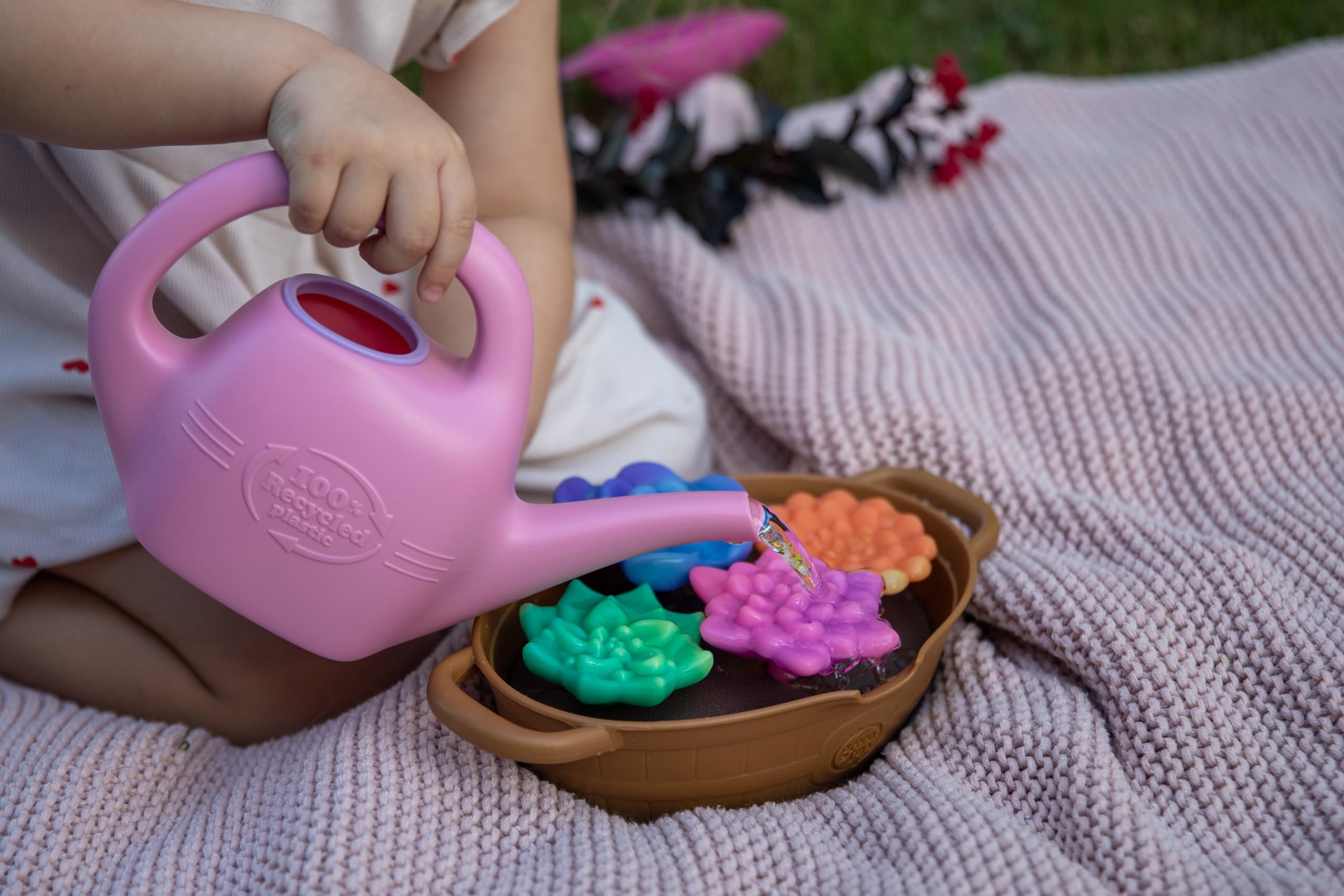 Green Toys watering can in child's hand showing small-hand friendly design benefit