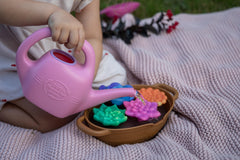 Green Toys watering can in child's hand showing small-hand friendly design benefit