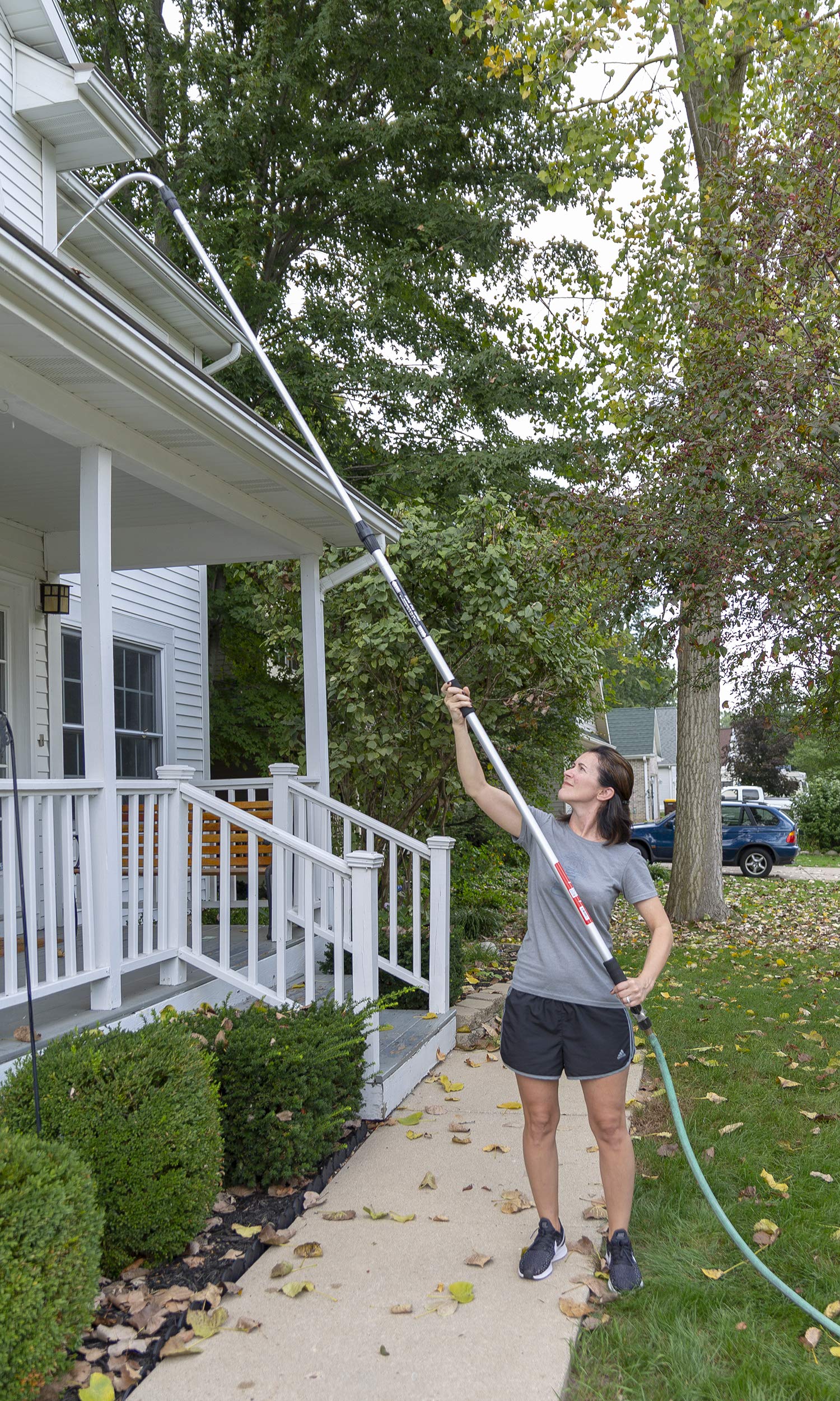 GUTTER MASTER pole fully extended in use reaching a second-story gutter for ladder-free cleaning