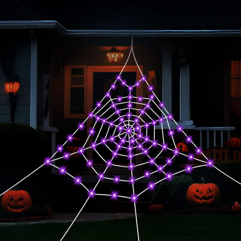 HKKDKTA spider web lit at night with purple glow enhancing spooky yard atmosphere