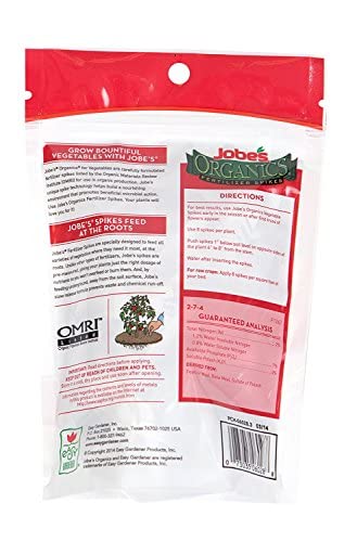 Jobe's Organics gardener inserting spikes in garden bed, convenient mess-free feeding