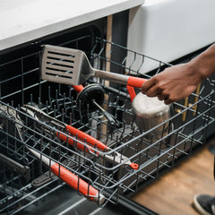 Kamado Joe brush held over hot grill demonstrating ergonomic reach and effective residue removal