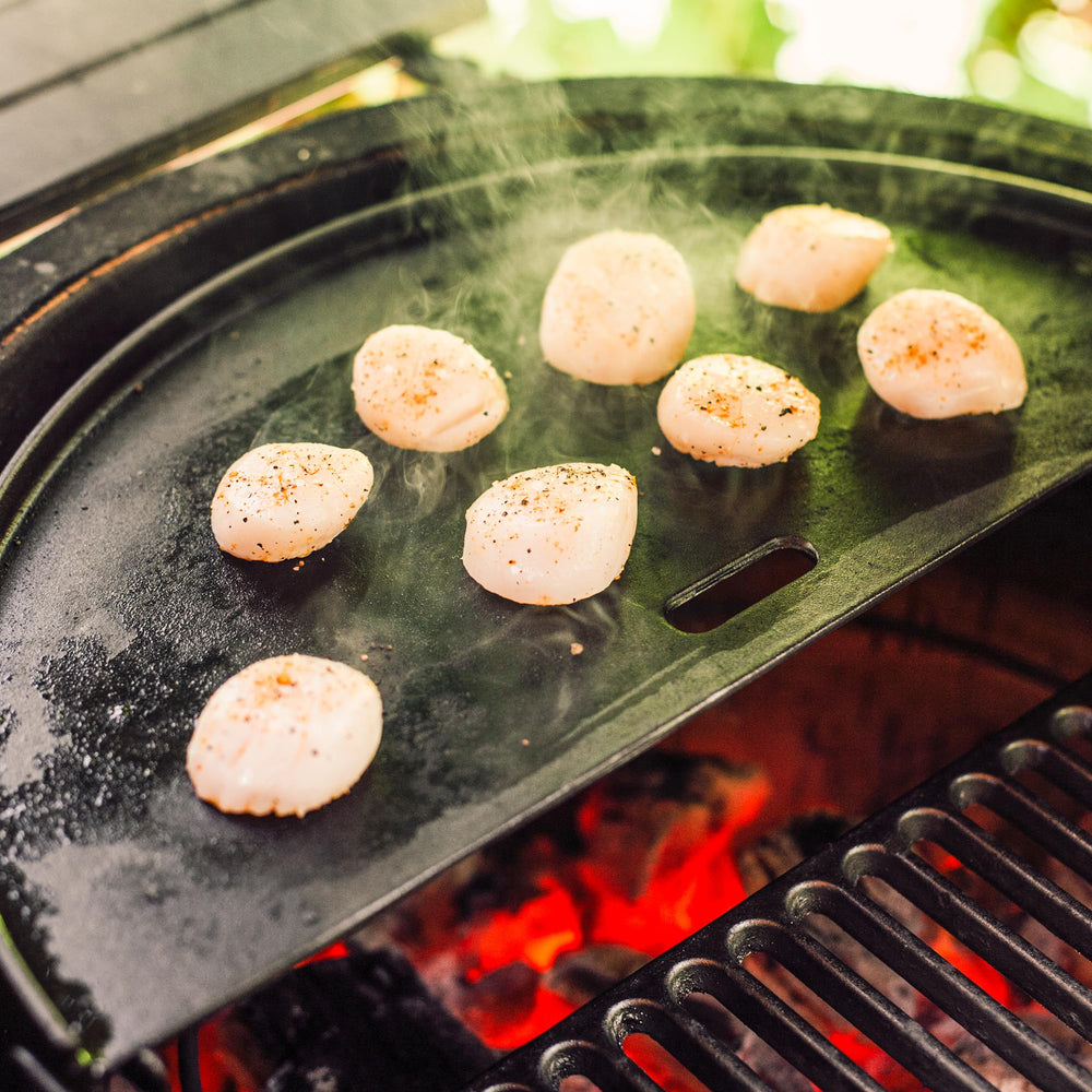Kamado Joe griddle next to hand for scale showing compact half-moon size