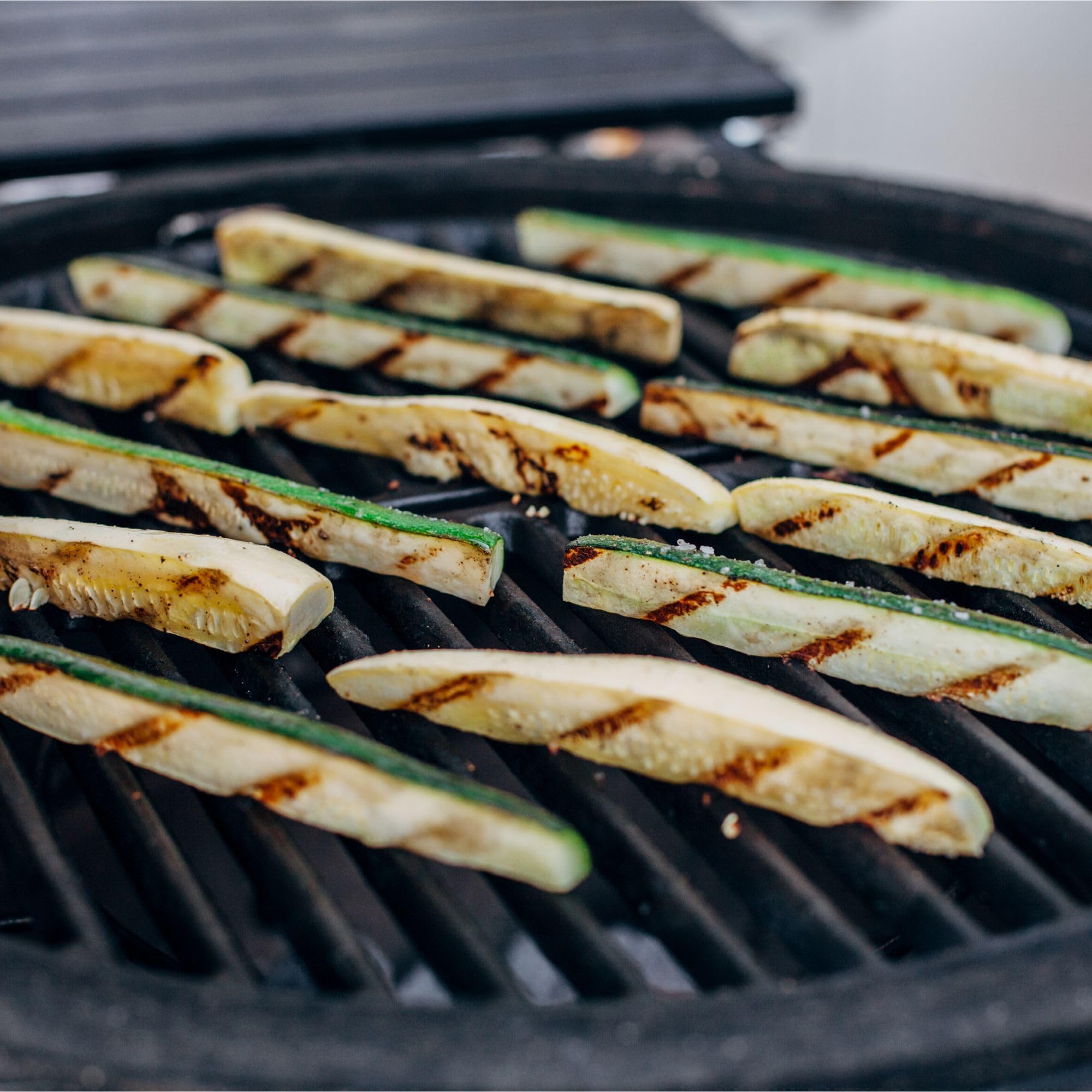 Kamado Joe grate beside tongs for scale showing compact half-moon fit and practical size