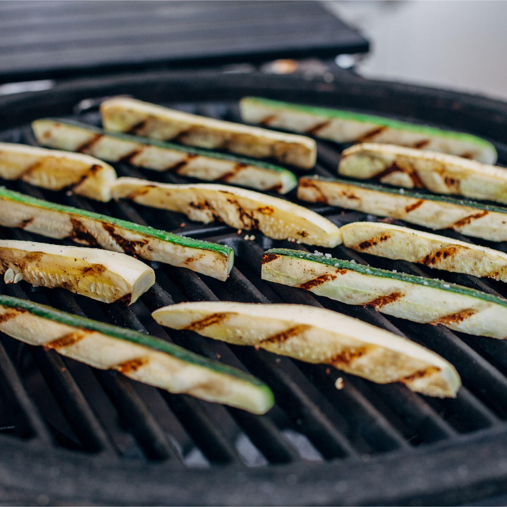 Kamado Joe grate beside tongs for scale showing compact half-moon fit and practical size