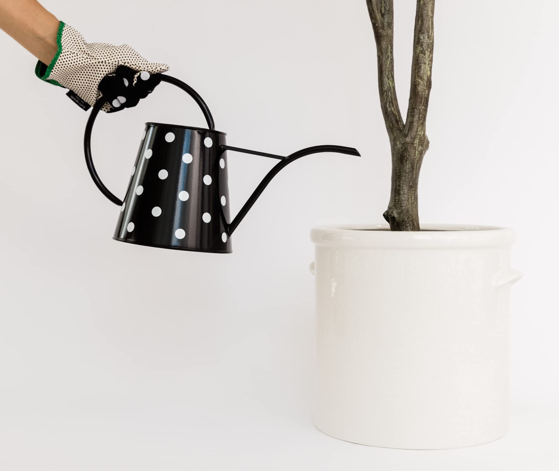 kate spade new york watering can beside a planter to show real size and capacity
