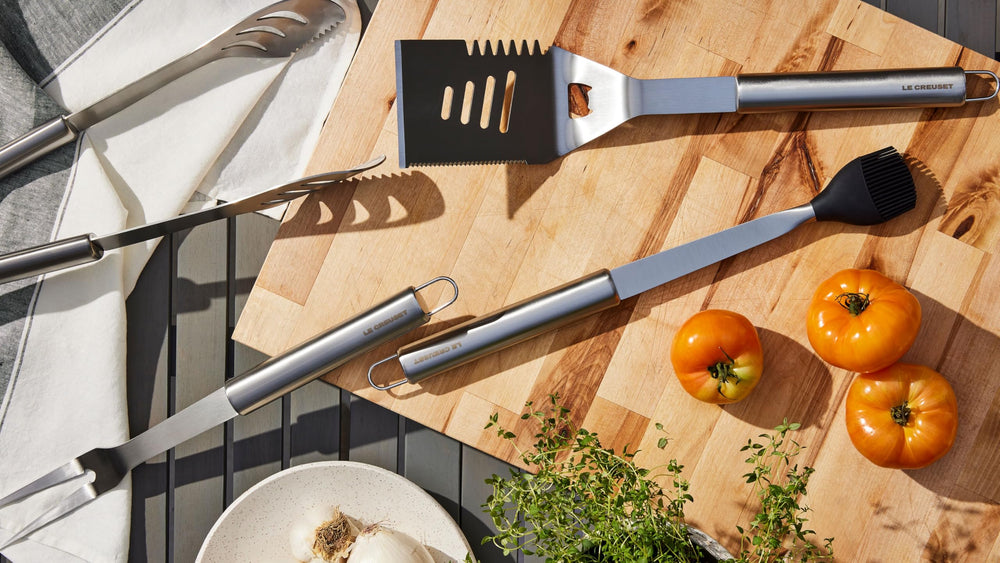 Le Creuset tongs and fork gripping steak on grill, demonstrating secure control and reach