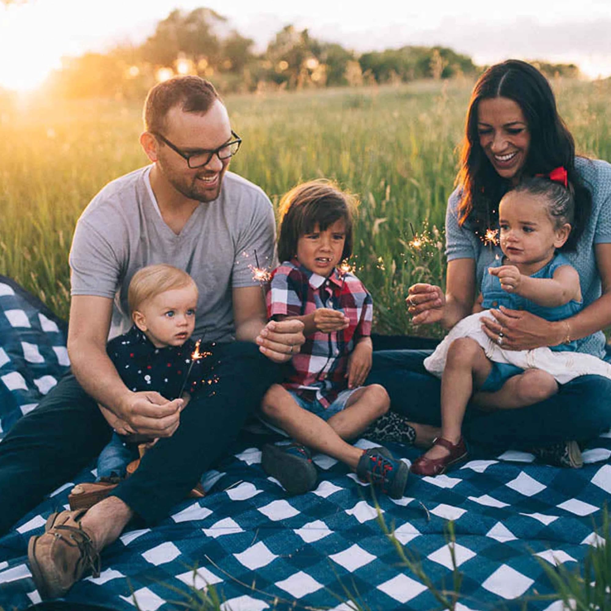 Little Unicorn blanket in use with family on grass providing comfortable seating benefit