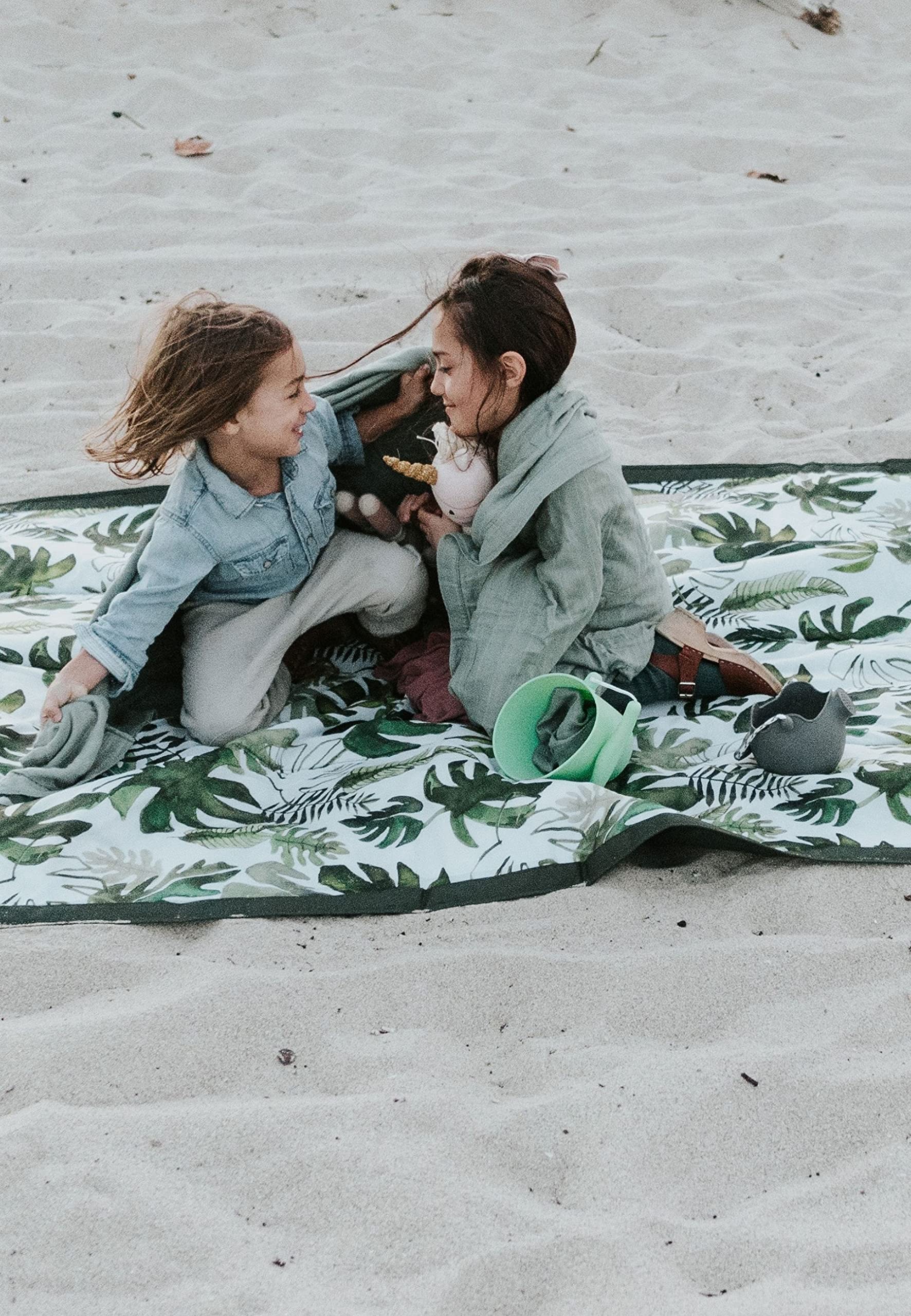 Little Unicorn blanket beside chair illustrating true 5x10 size and ample coverage benefit