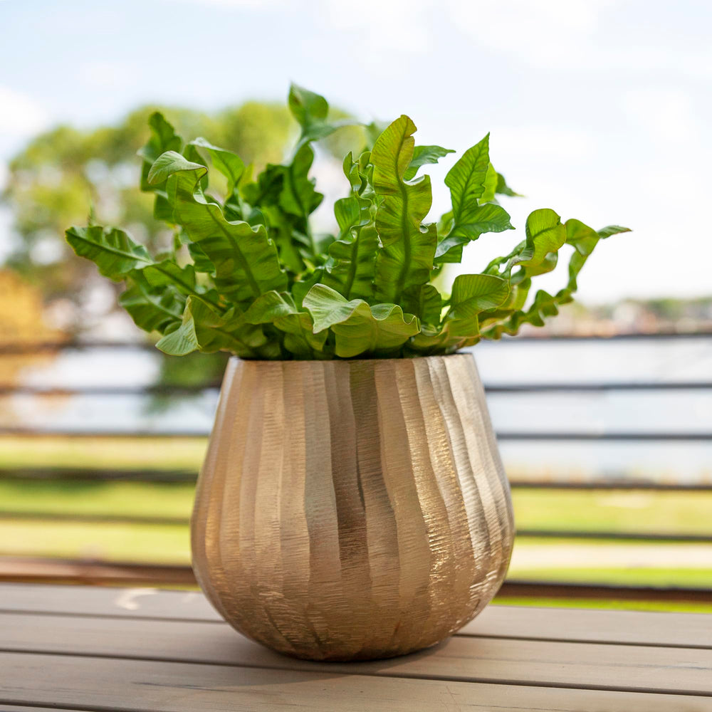 Luene planter staged in living room adding warm metallic accent to decor