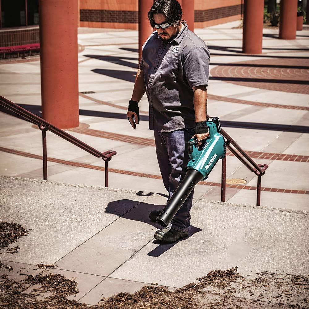 Makita XBU03SM1 in use clearing leaves in yard demonstrating quieter cordless benefit