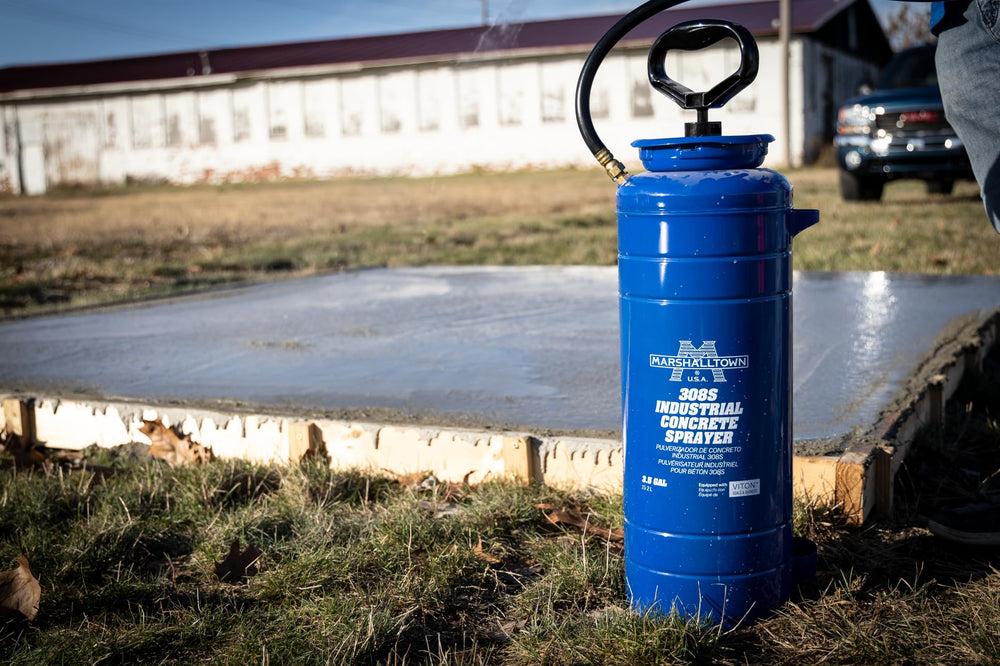 MARSHALLTOWN sprayer next to hardhat showing portable 3.5 gallon capacity