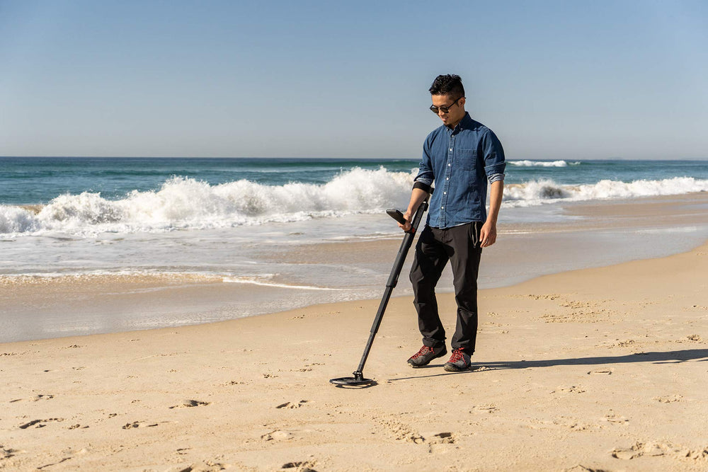 MINELAB GO-FIND 44 used on beach with user finding a coin for beginner-friendly hobby benefit