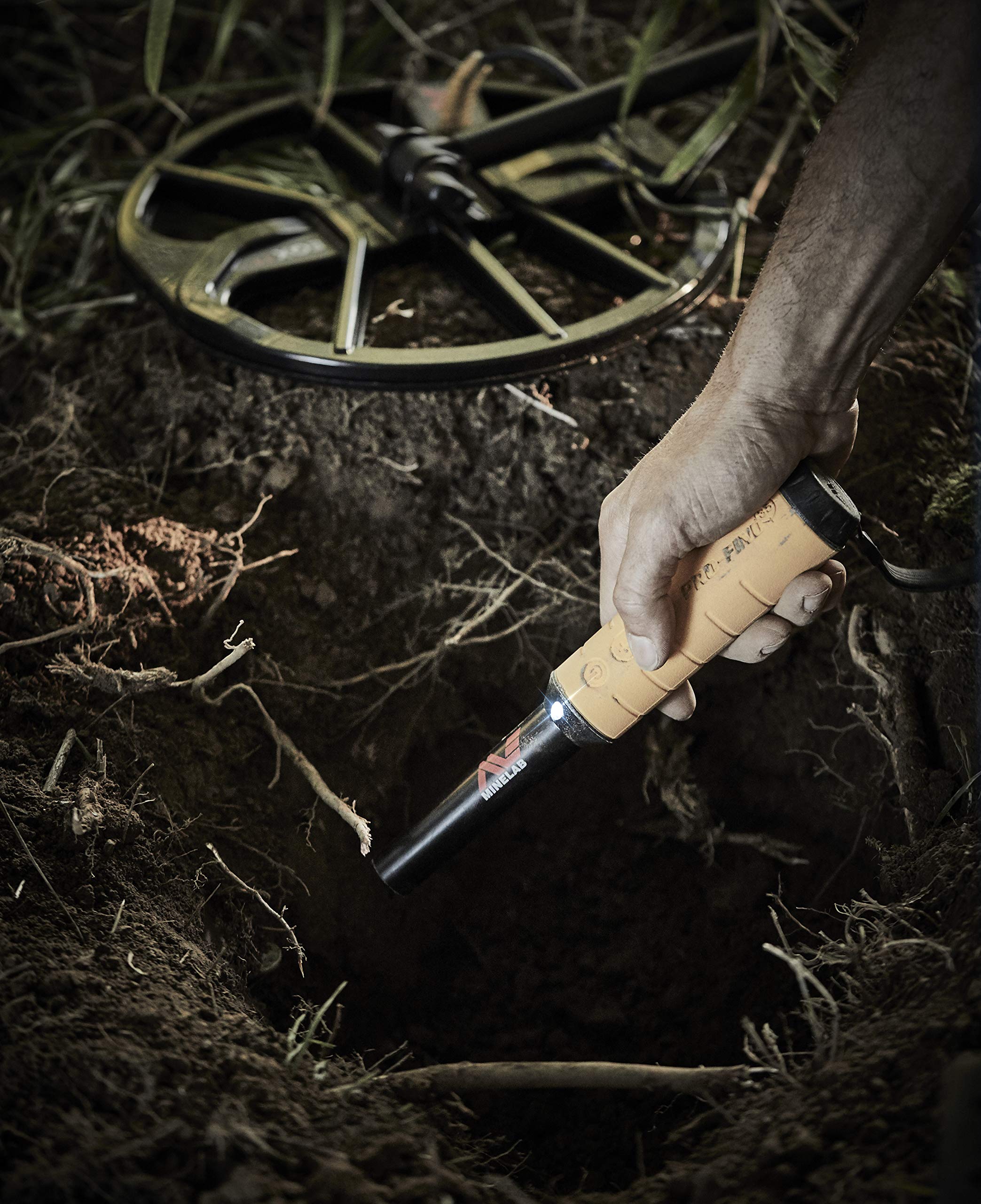 MINELAB PRO-FIND 35 held in hand over sand, demonstrating ergonomic control and quick pinpointing