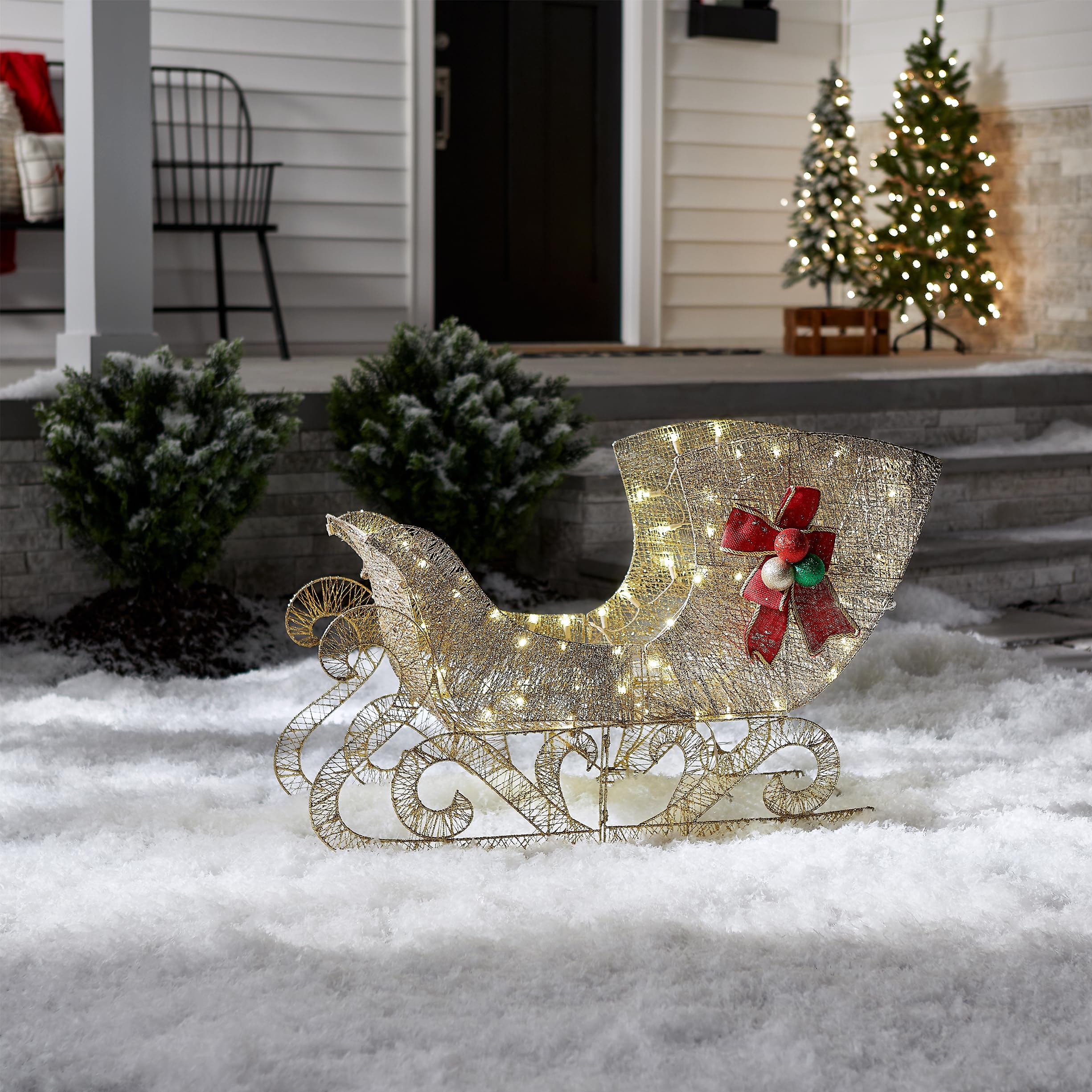 National Tree Company sleigh lit in yard at night providing warm outdoor ambiance