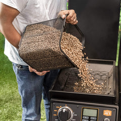 Oklahoma Joe's scoop transferring pellets into hopper for neat loading