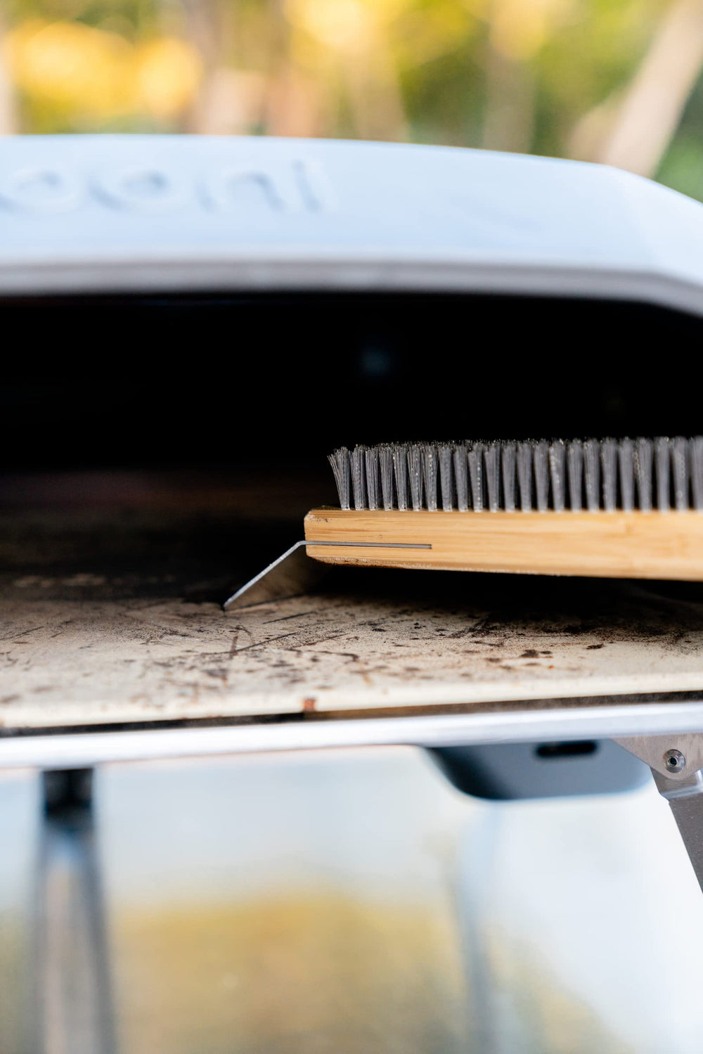 ooni pizza oven brush in use cleaning oven interior for faster post-bake cleanup