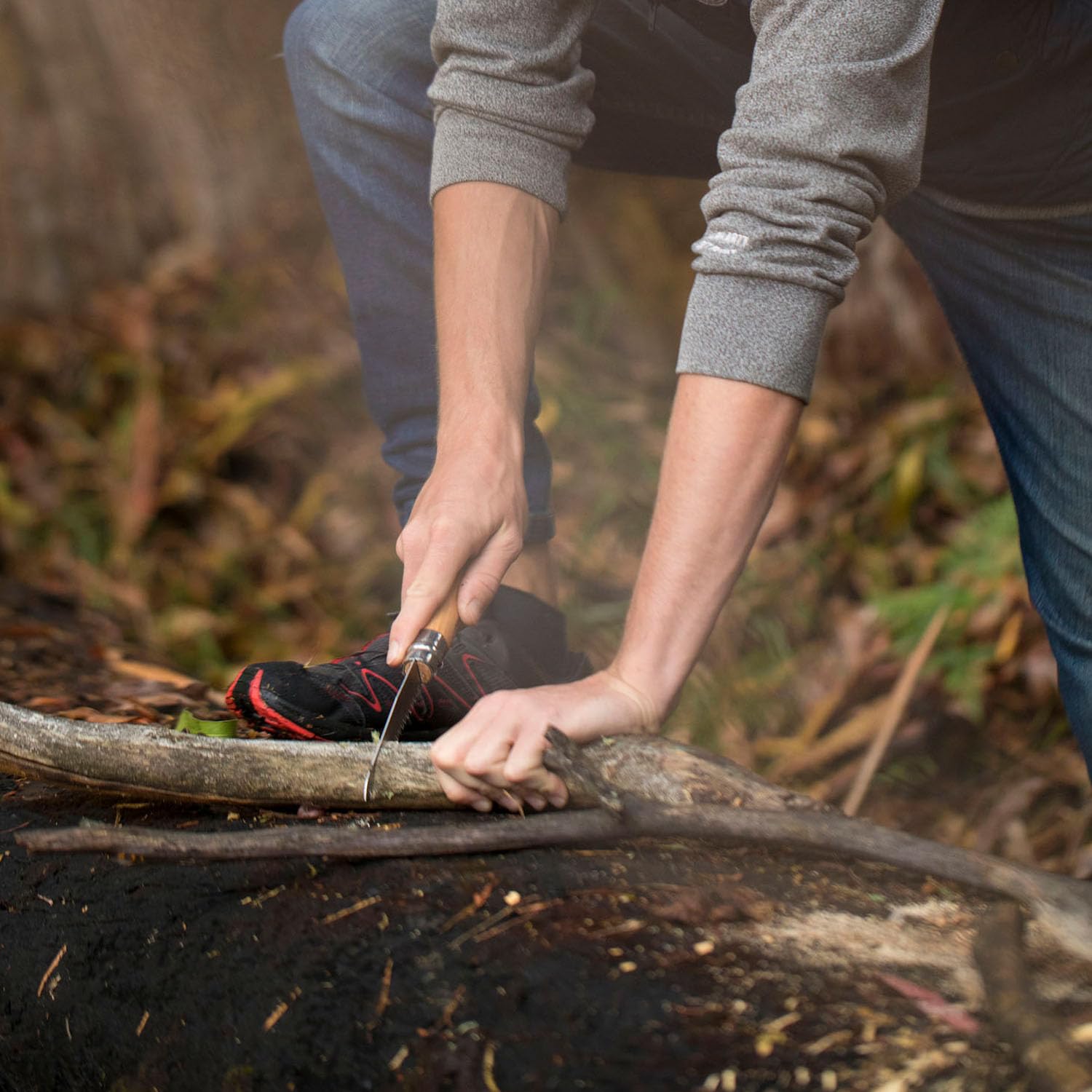 Opinel saw slicing camp wood beside fire for fast campsite preparation