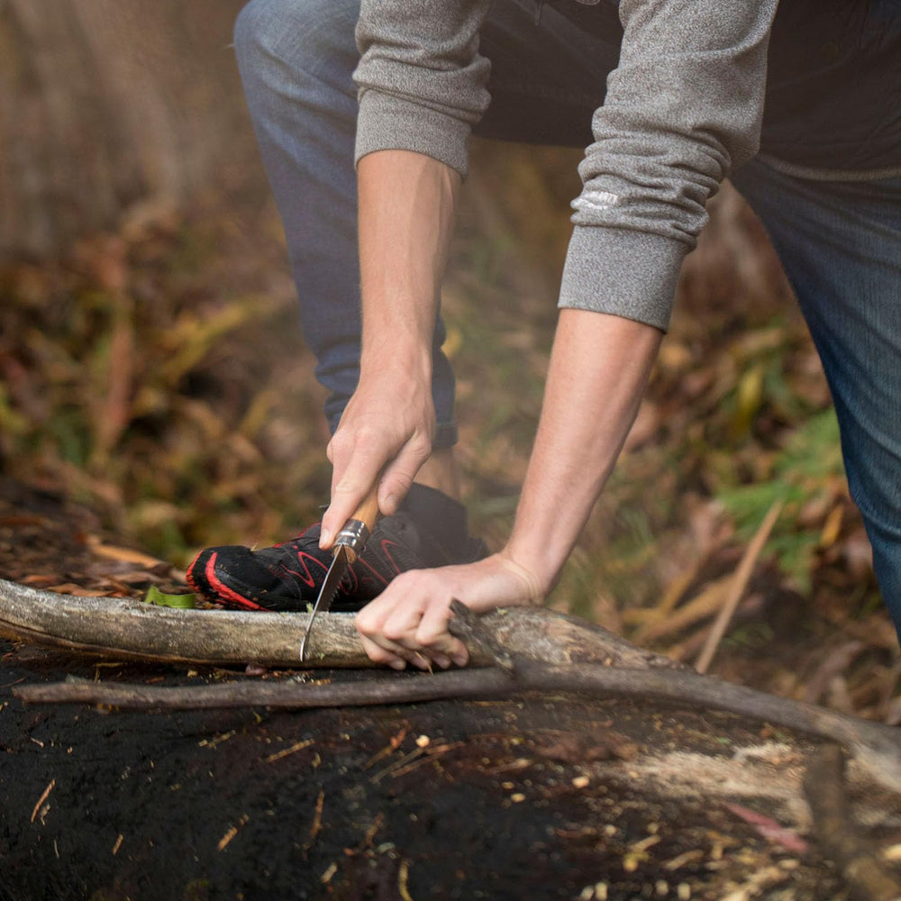 Opinel saw slicing camp wood beside fire for fast campsite preparation