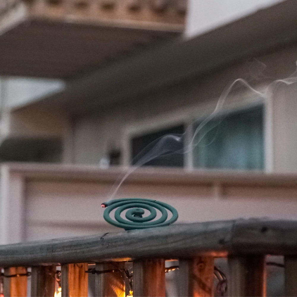 PIC coil burning in holder outdoors showing steady smoke for mosquito reduction