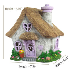 PRETMANNS fairy house placed in a flower bed adding whimsical décor