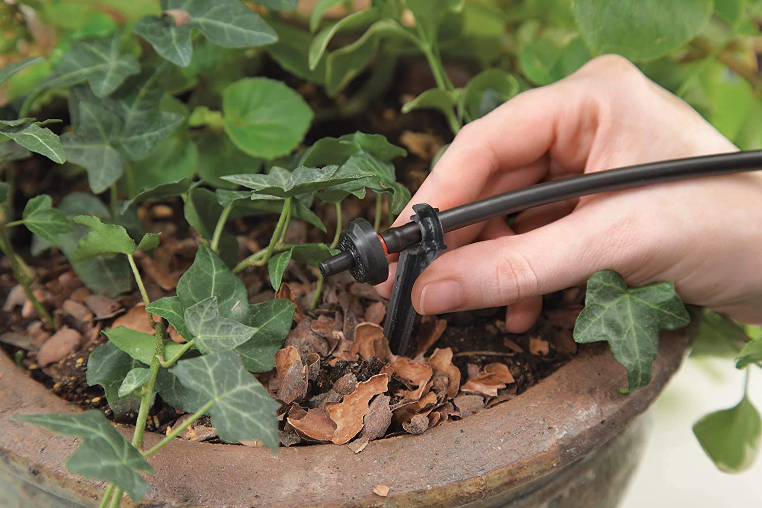 Raindrip scale photo next to hand showing compact parts and easy handling during install