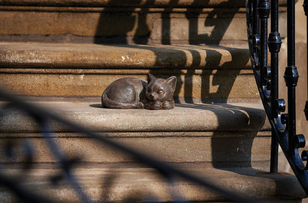 Roman bronze sleeping cat on garden stone ledge suggests durable outdoor accent and cozy style