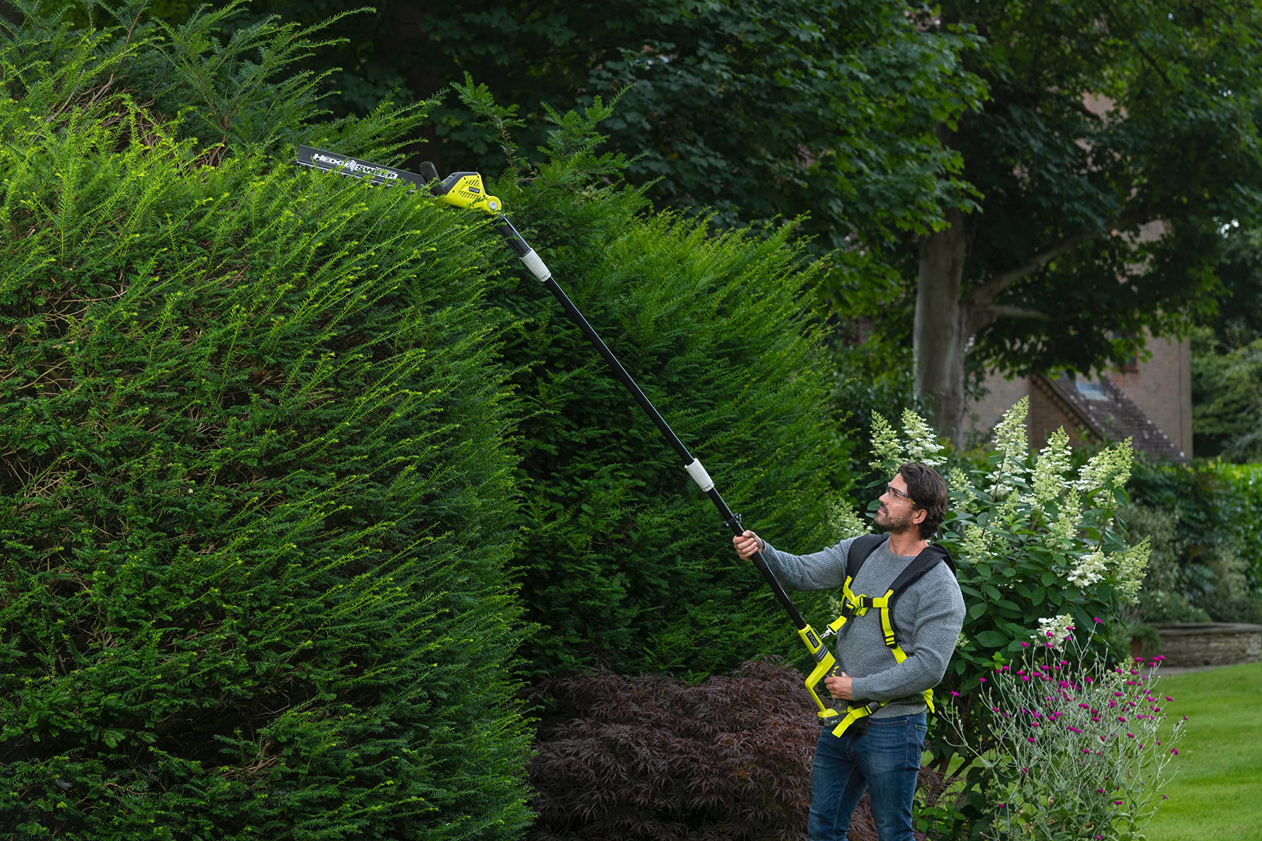 RYOBI trimmer in use cutting dense hedge for efficient yard maintenance