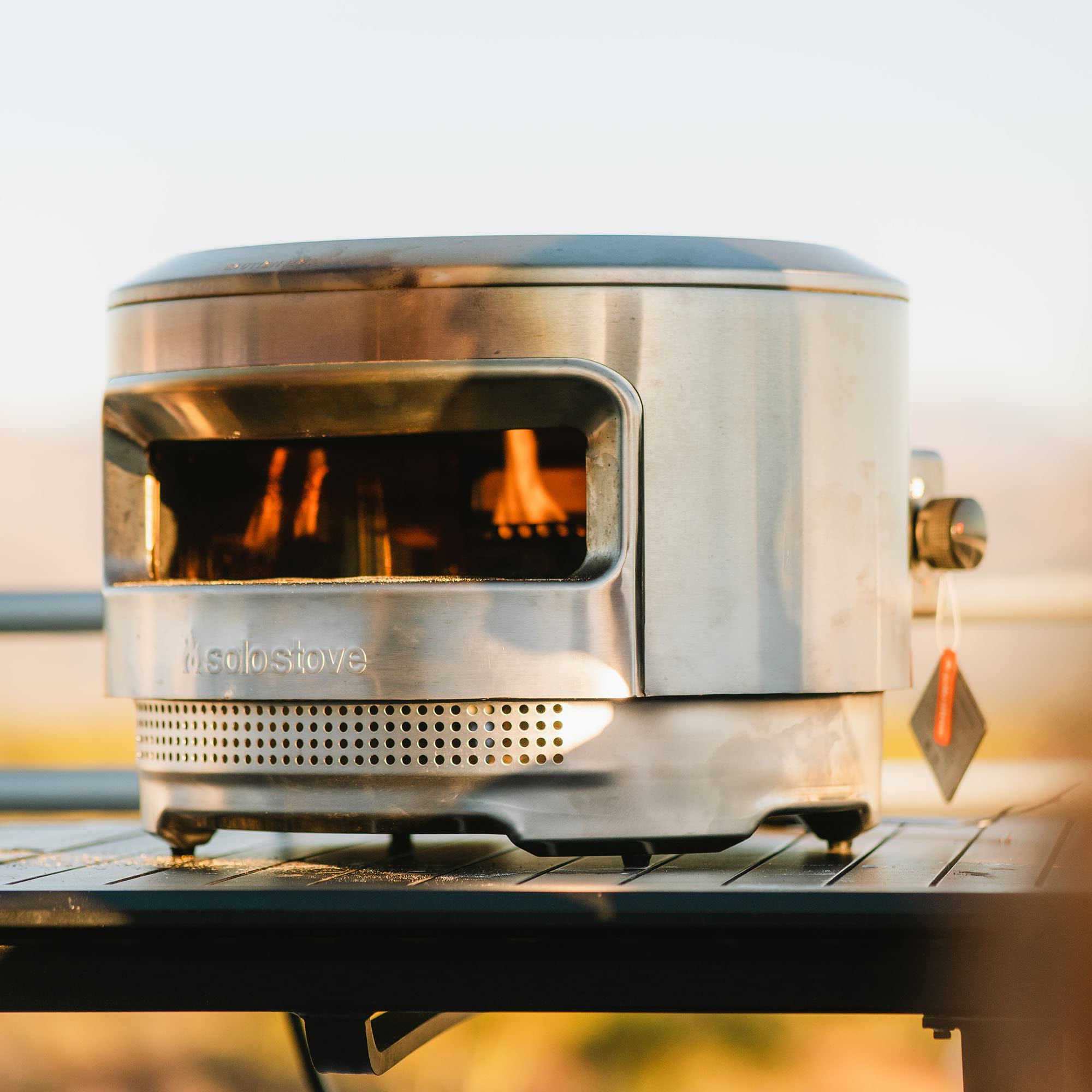 Solo Stove gas burner beside hands showing compact size and light handling benefit
