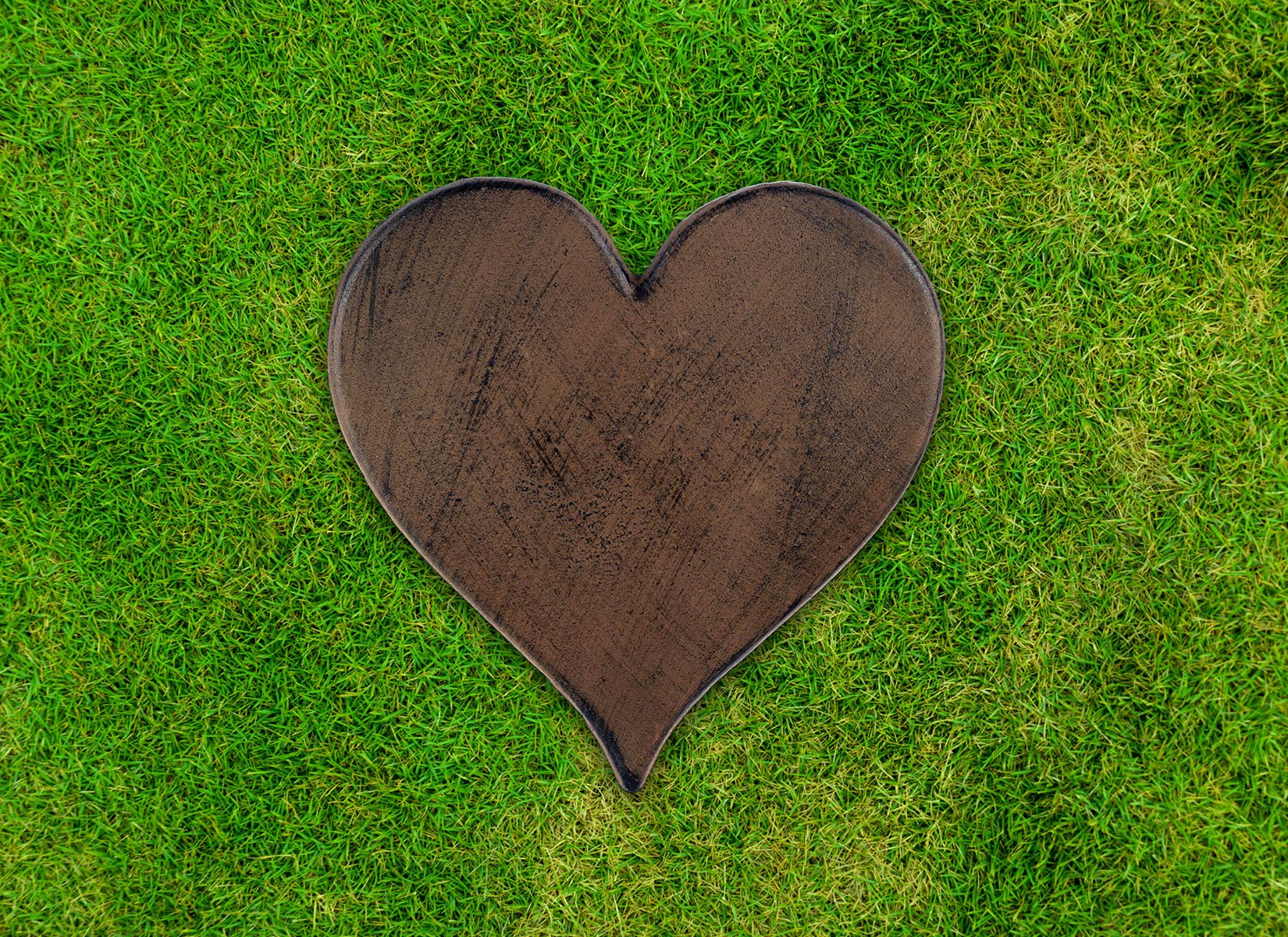 Sunset Vista heart cast iron stepping stone placed by garden path offers lasting decorative pathway solution