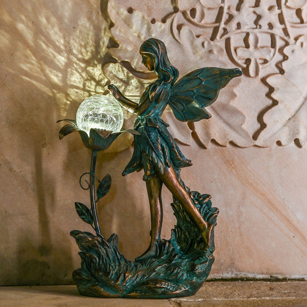 TERESA'S COLLECTIONS nighttime glow of fairy statue providing soft garden illumination